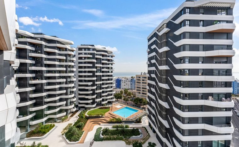 A modern apartment building in Parque das Nações, Lisbon, with sleek glass balconies overlooking a marina on the Tagus River.